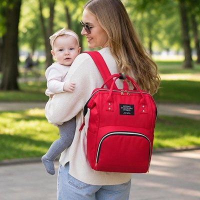 Sac a dos a langer rouge sang porté par une maman avec son enfant